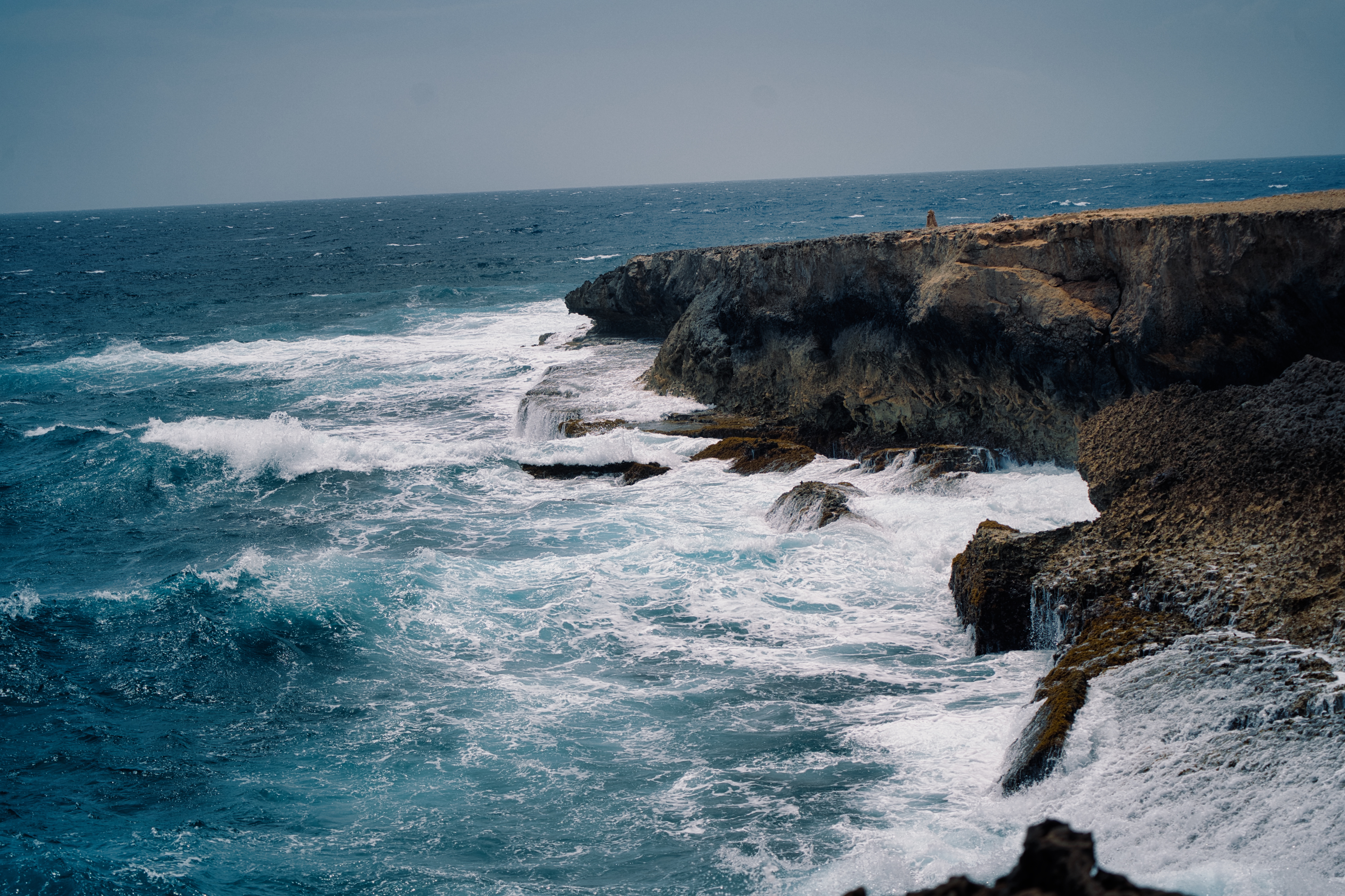 Rough ocean waves crashing against a dark rocky cliff