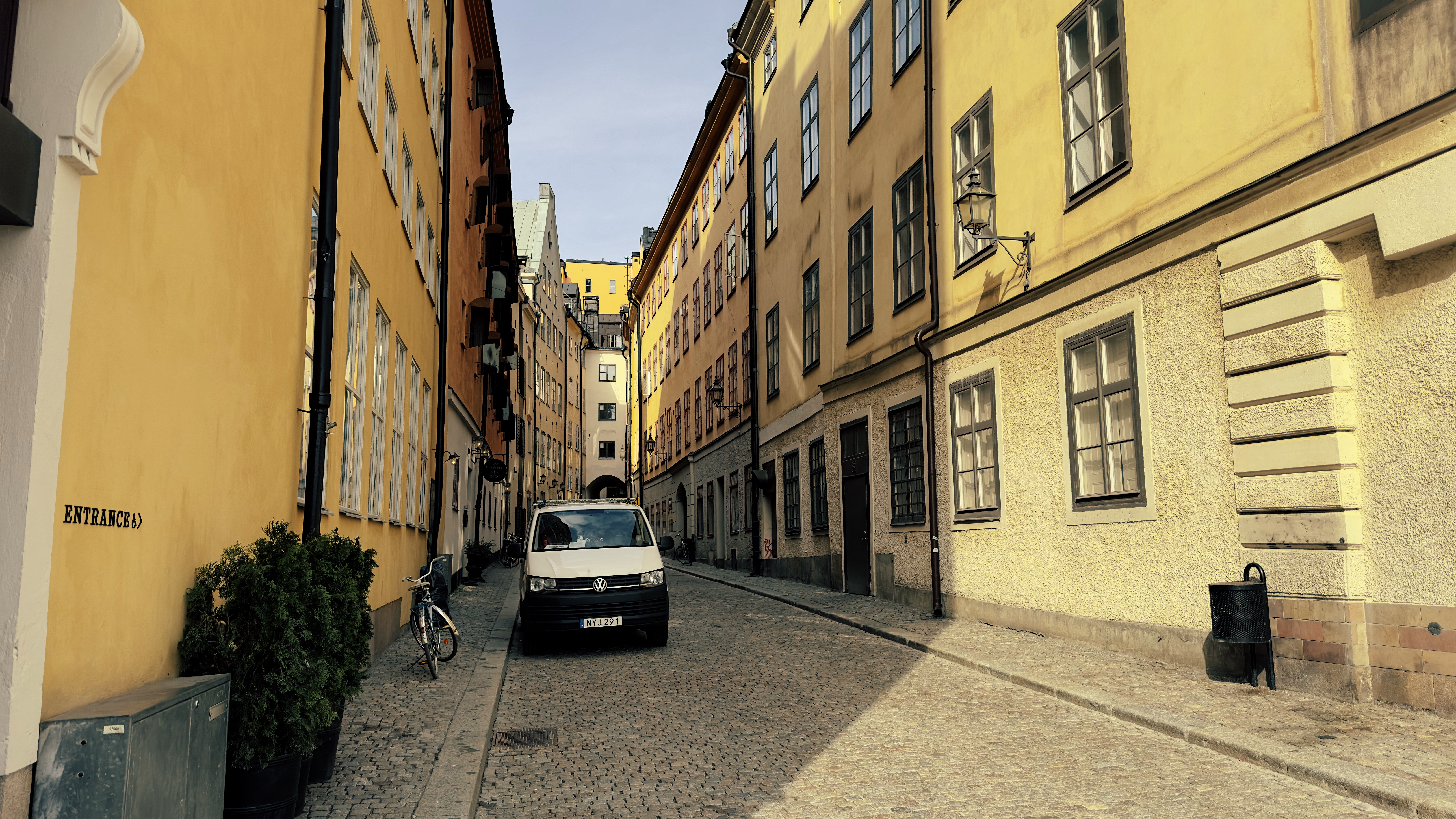 A Stockholm Gamla Stan cobblestone alley with yellow and ochre plaster buildings and a parked van