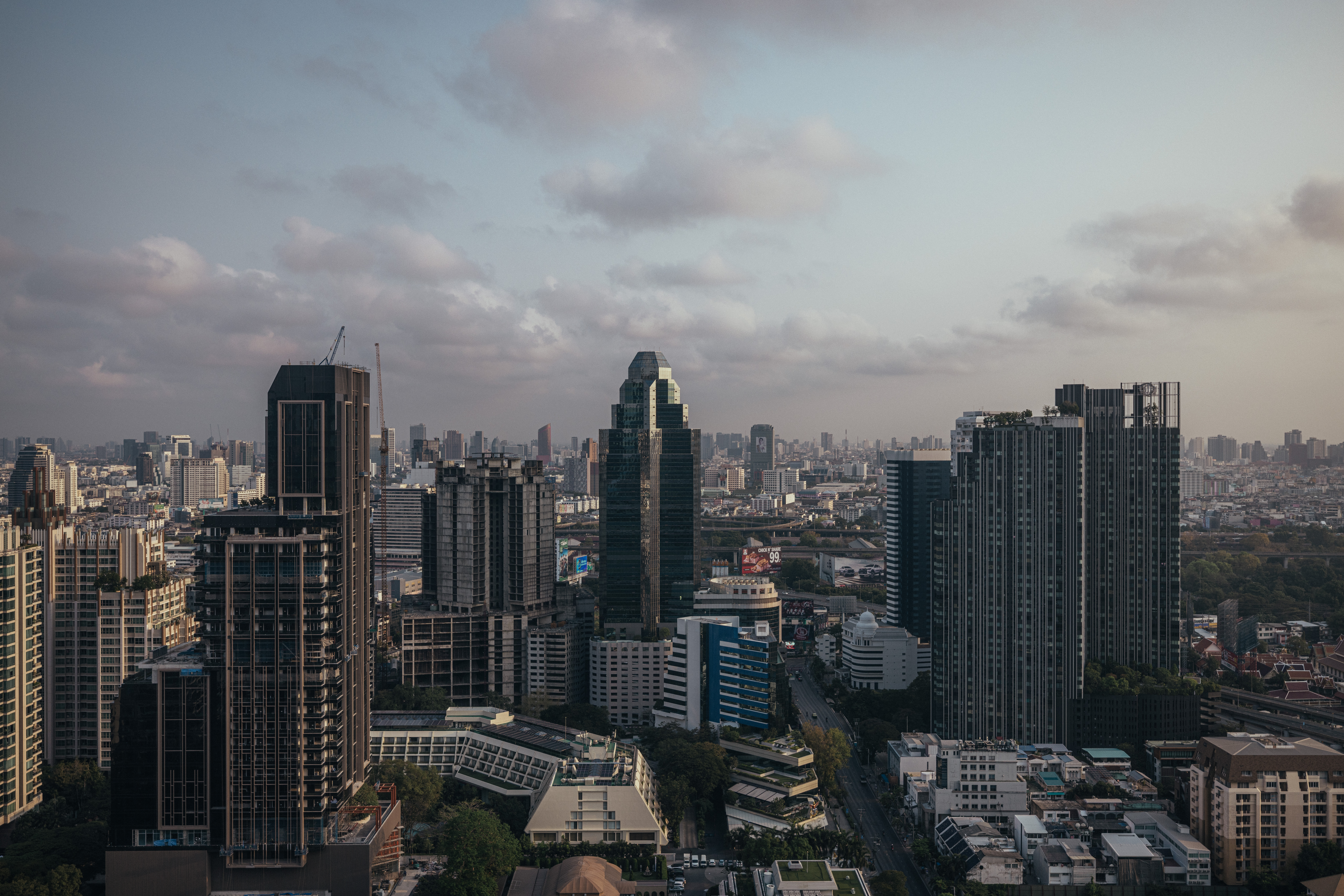 A wide Bangkok skyline seen from a high-rise in late afternoon